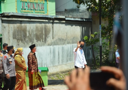 Presiden Joko Widodo melambaikan tangannya menyapa masyarakat dan anak -anak yang memanggilnya  